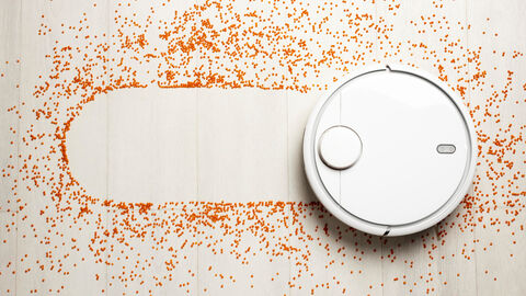 Ein Saugroboter fährt über eine Ausstreuung von Papierkonfetti und hinterlässt damit eine Konfetti freie Spur.