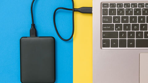 Eine SSD-Festplatte ist mit einem Kabel an ein Notebook angeschlossen. Der Blick erfolgt von oben.