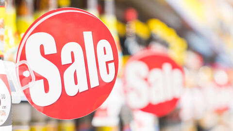 Ein Rabattzeichen hängt vor einem verschwommen abgebildeten Regal